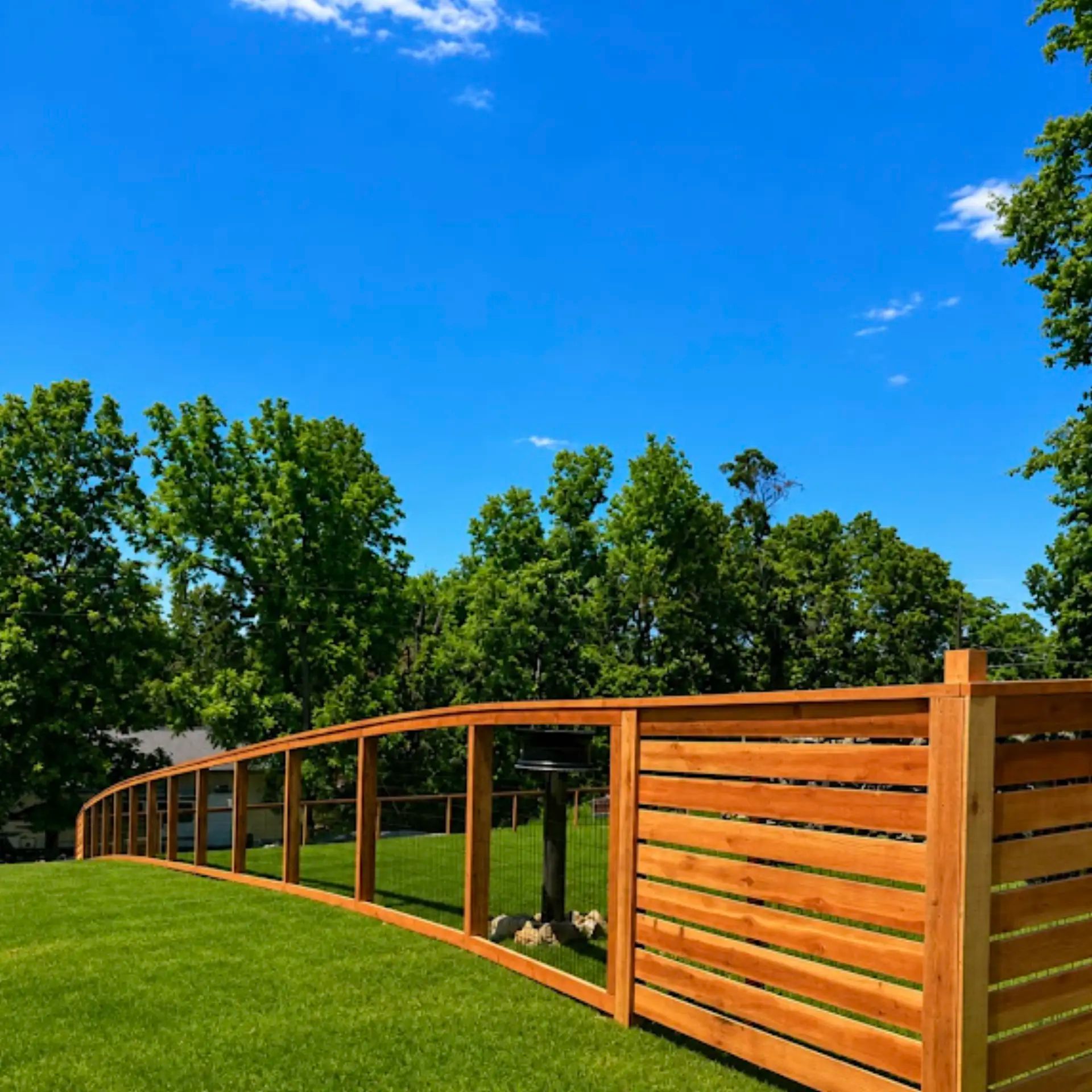 Custom 5-foot-tall open view redwood fence with black wire mesh panels and horizontal redwood accent sections in Rogers, Arkansas.
